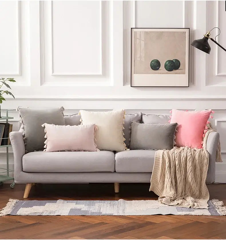 Light gray upholstered sofa with wooden legs featuring decorbites fringed tassel velvet pillowcases in pastel shades