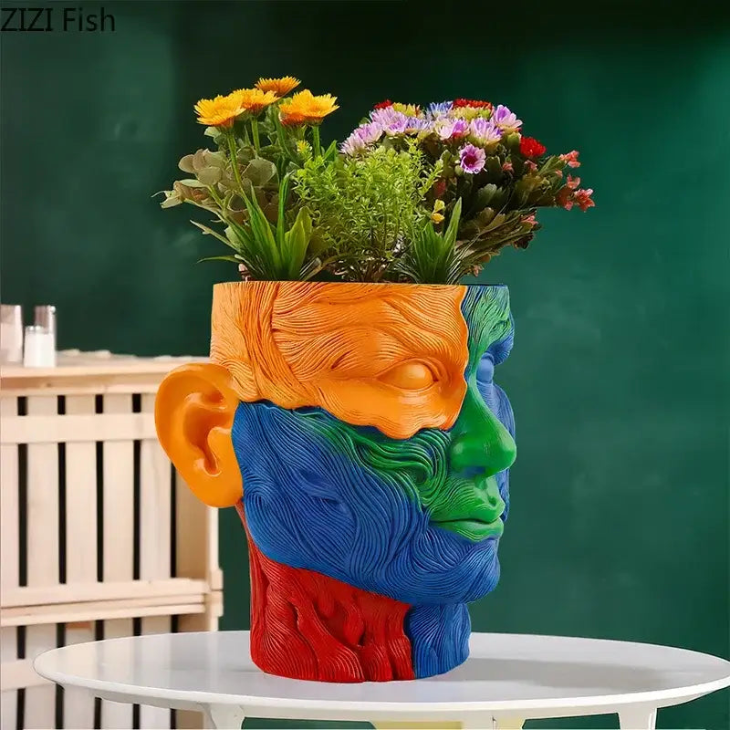A colorful resin human portrait vase with orange blue green and red sections holding artificial flowers decorbites colorful human decor