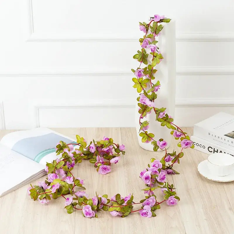 A delicate artificial rose flowers vine garland with soft pink blossoms and lush green leaves for living room decor