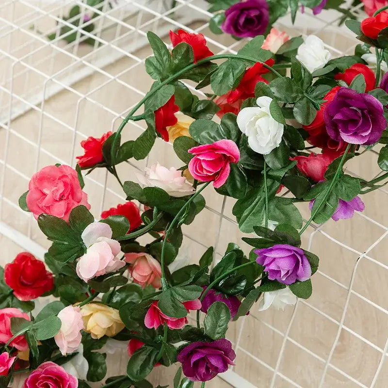 Vibrant multi colored rose flowers vine garland with red pink white purple blooms and glossy green leaves for living room decor