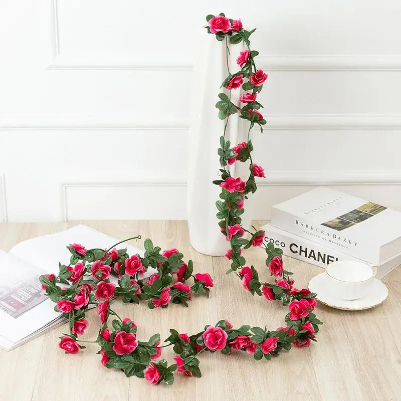A vibrant red rose flowers vine garland made of synthetic material with lush green leaves for living room decor