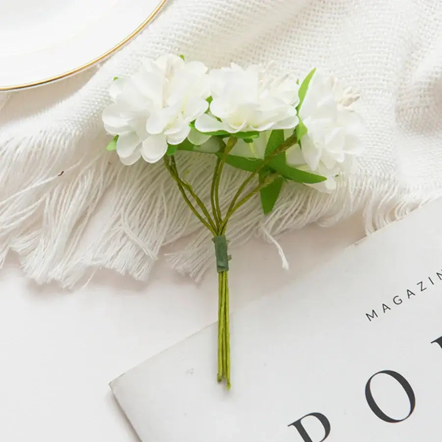 A delicate white artificial flower stamen bouquet with green stems and leaves for living room decor