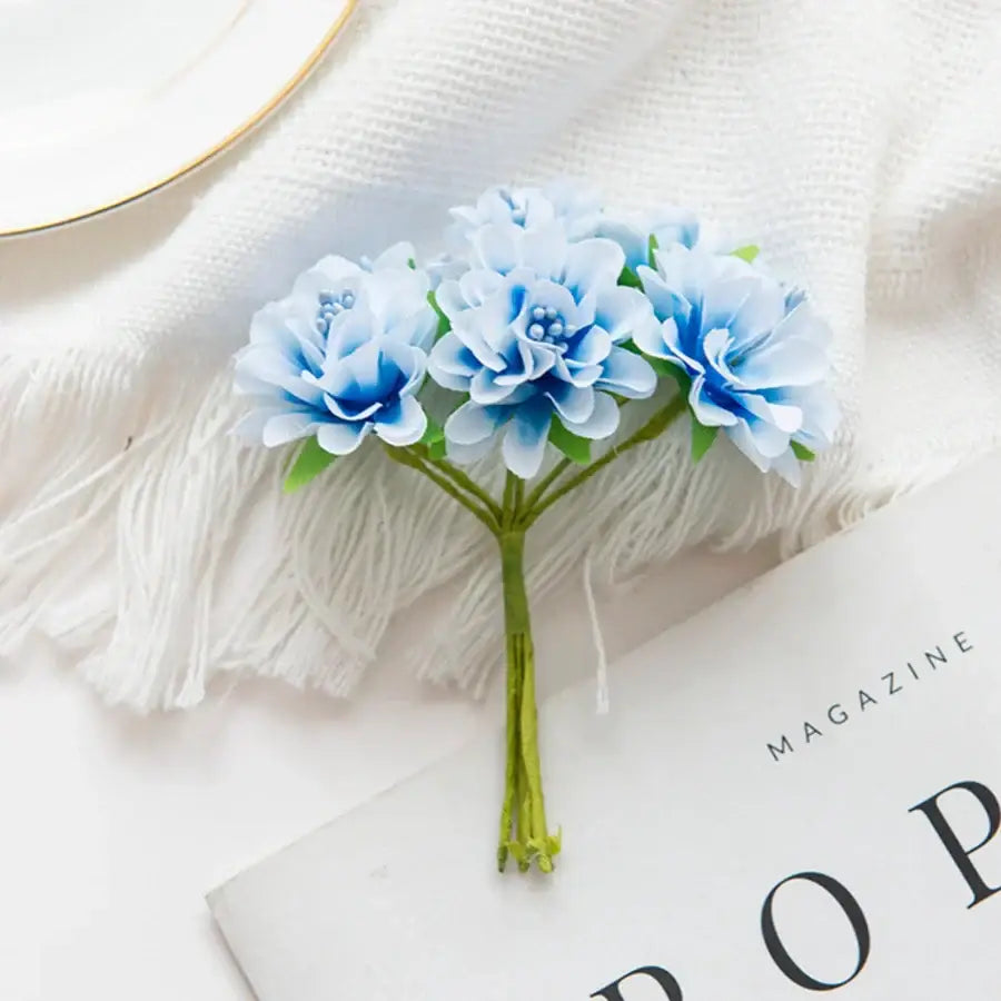 A delicate flower stamen bouquet of three light blue artificial flowers with darker centers for living room decor