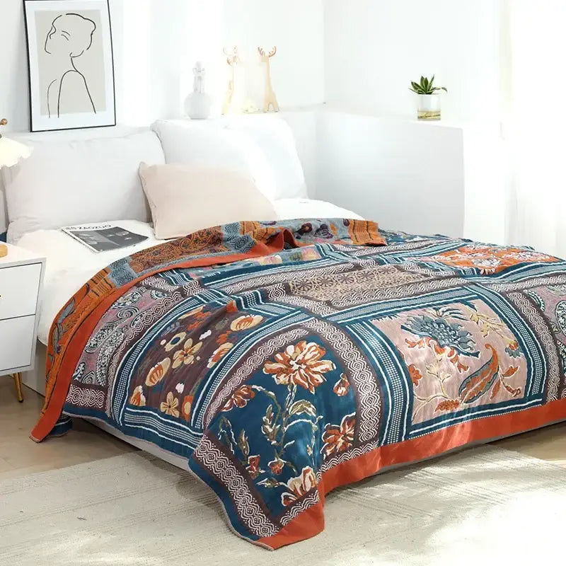 A cozy nordic throw blanket with intricate floral and paisley patchwork in teal rust orange and muted pink tones