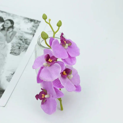Delicate purple butterfly orchid bouquet with realistic silk petals and green stems in a clear glass vase for decor