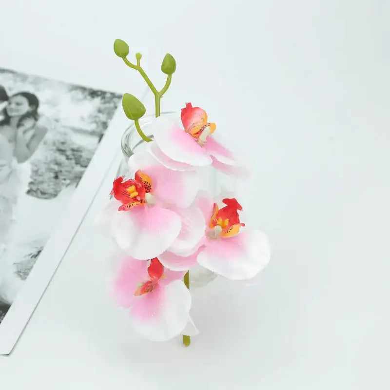 Delicate pink and white silk butterfly orchid bouquet with vibrant red centers in clear glass vase for wedding decor