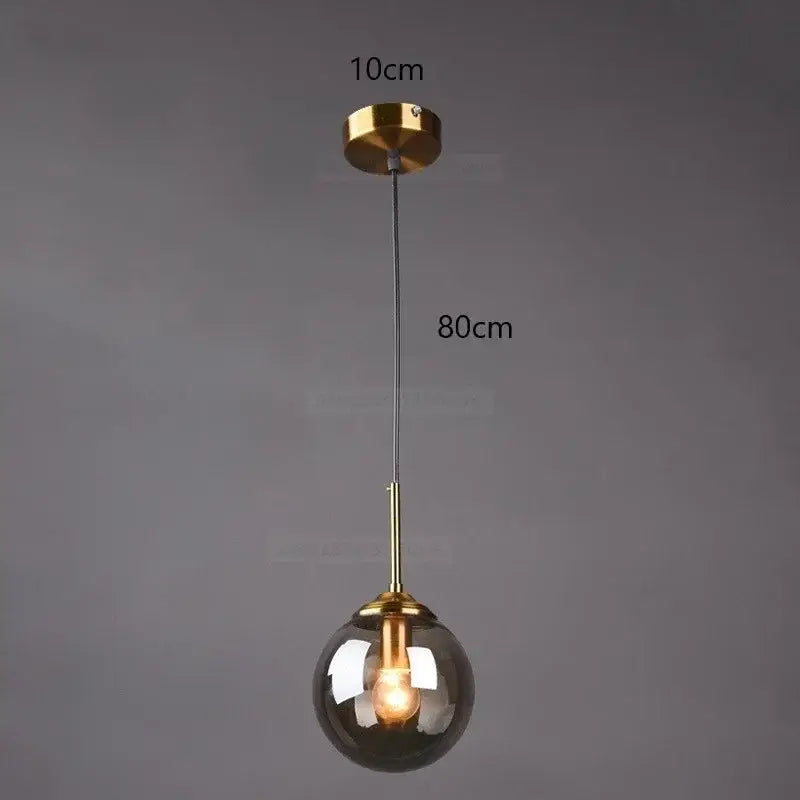 A modern pendant light with a gold-toned metal fixture and a smoked gray glass ball ideal for bedroom decorbites gray glass decor