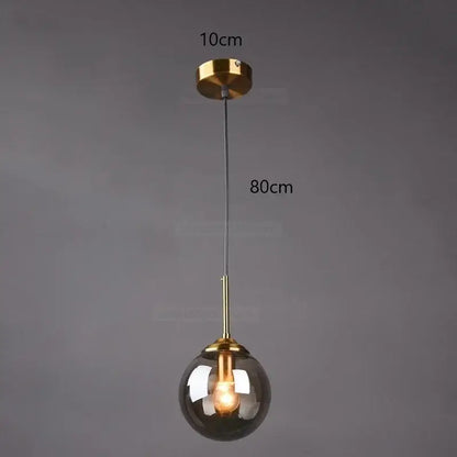 A modern pendant light with a gold-toned metal fixture and a smoked gray glass ball ideal for bedroom decorbites gray glass decor