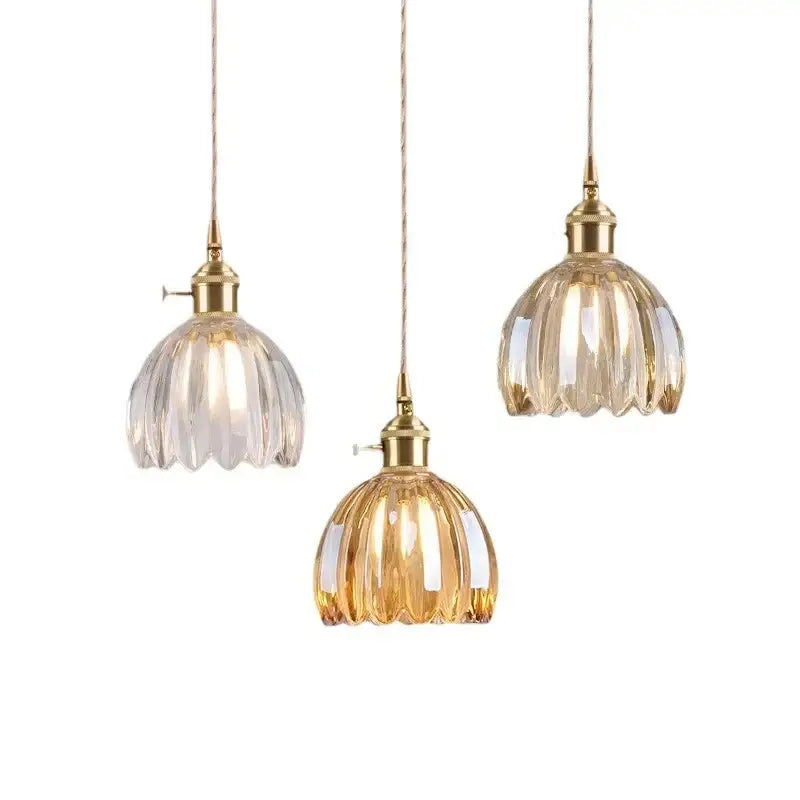 Three elegant vintage amber and clear glass pendant lights with gold-toned metal fixtures and iron finish
