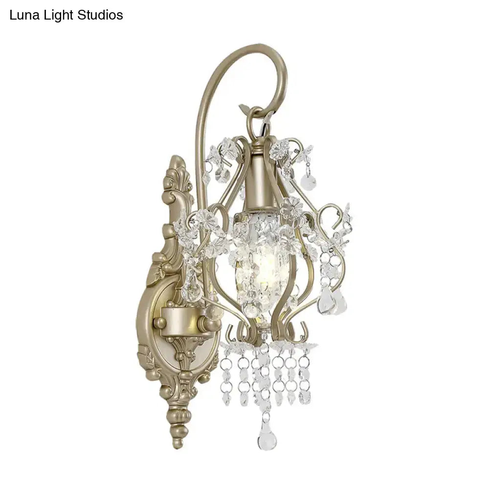 Antique brass wall lamp with clear crystal beaded strand and ornate scrollwork for vintage bedroom lighting
