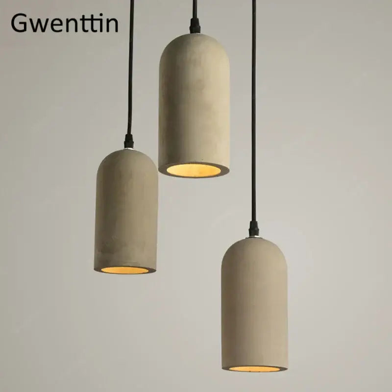 Three beige decorbites cement pendant lamps with black cords and warm yellow interiors for dining room lighting