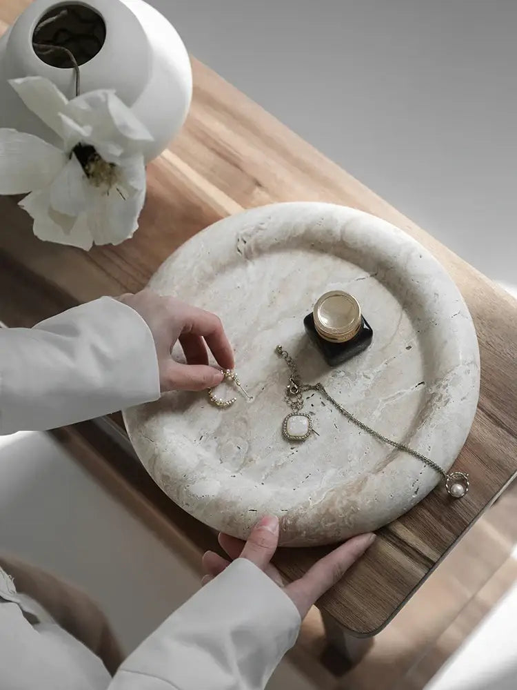 A delicate gold-toned hoop earring on a vintage beige travertine serving tray by decorbites for bedroom vanity decor