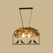 Vintage bird cage iron hanging light with black metal frame pink roses greenery and three exposed bulbs with bird figurines