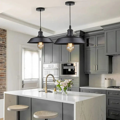 Two black decorbites black farmhouse pendant lights with exposed filament bulbs hang above kitchen island