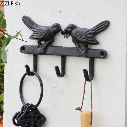 Vintage black iron bird hook wall shelf featuring two birds on a bar with three hooks for entryway storage