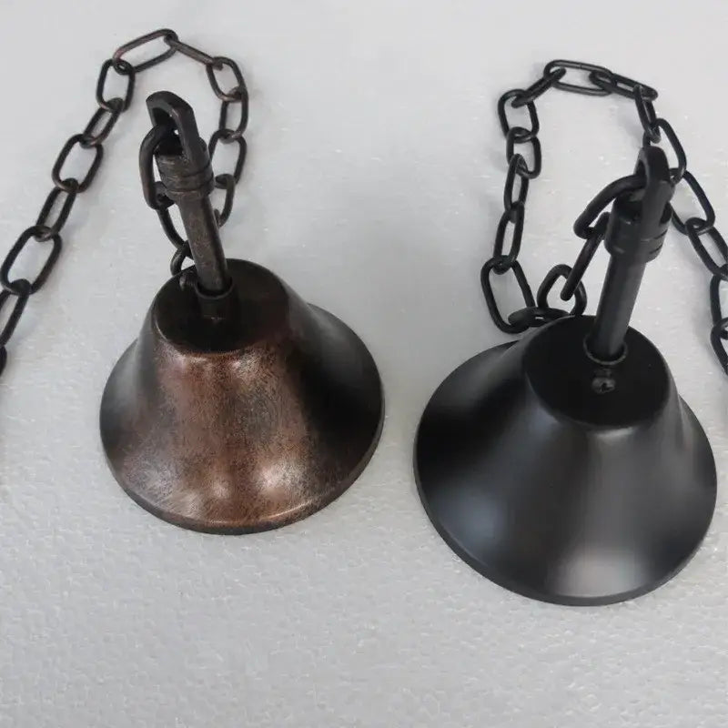 Two hanging bells with rustic bronze and matte black finishes on chains complement the decorbites black vintage pendant lamp