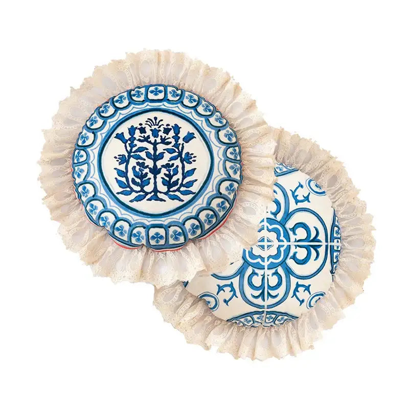 Two round cushioned pillow covers with vintage blue and cream peacock toile pattern and cream lace ruffles for living room