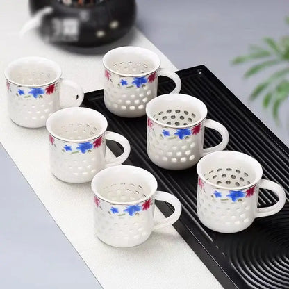 Set of six vintage blue and white ceramic tea cups with perforated sides arranged on a black tray cup set