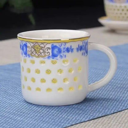 White ceramic tea cup with blue floral and gold patterns yellow gold rim and circular cutouts in vintage cup set