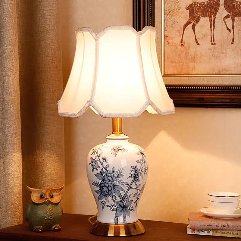 White porcelain table lamp with blue floral design gold-toned base and off-white pleated shade decorbites blue white