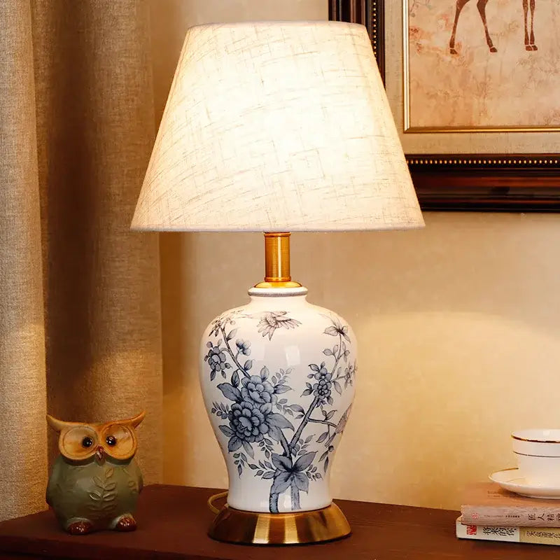 Vintage blue and white porcelain table lamp with floral ceramic design gold-toned base and off-white fabric shade decorbites blue white