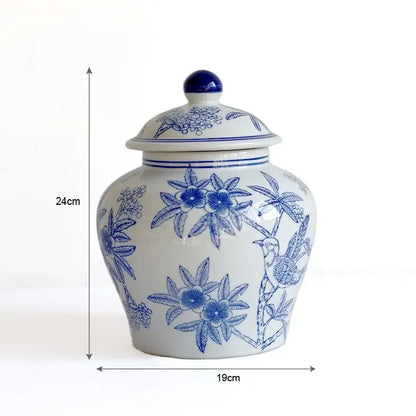 A white ceramic porcelain vase with blue white floral and bird design and a glossy blue knob lid for living room decorbites blue white decor