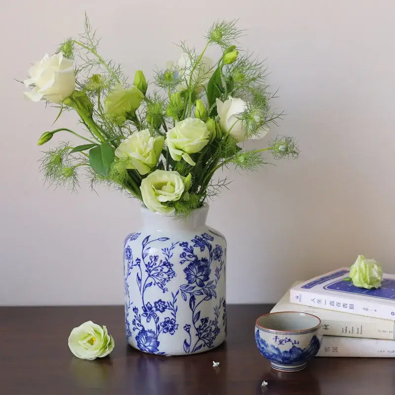 A white porcelain vase with intricate blue white floral patterns holds pale green and cream roses for living room decorbites decor