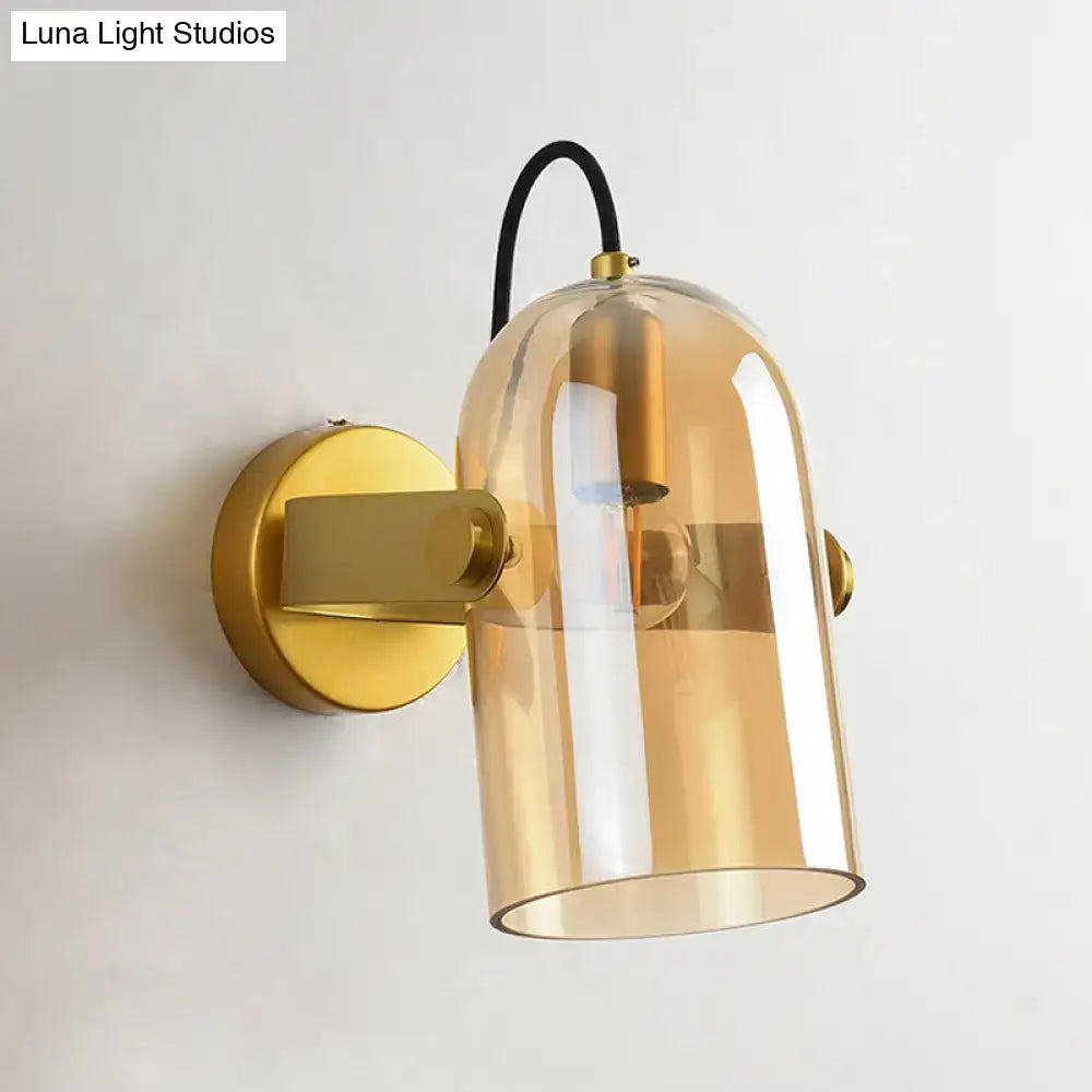 Gold-toned swivel shade cloche bedside sconce with translucent amber glass dome and black cord for bedroom use
