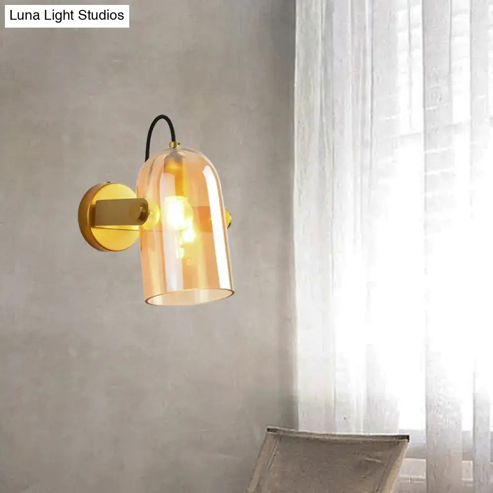 A vintage brass amber glass swivel shade cloche bedside sconce with a brass bracket and black cord for bedroom use