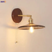 Vintage brass wall sconce with amber glass shade and dark brown wooden backplate featuring a pull chain switch