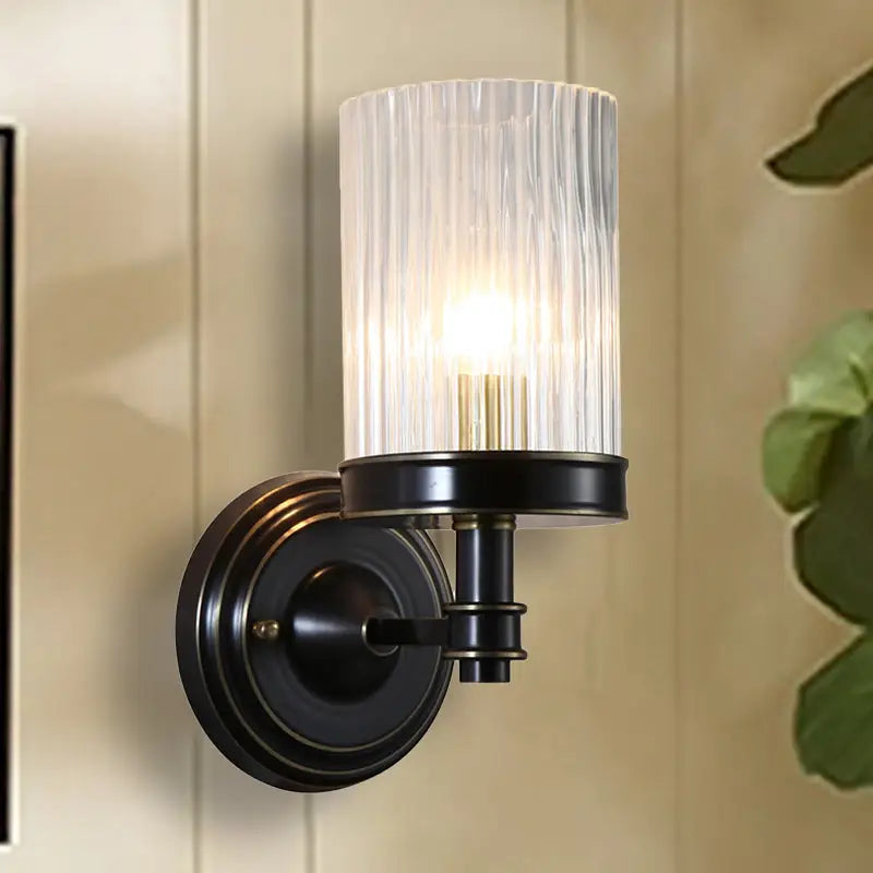 Vintage brass and black wall lamp with clear ribbed glass cylinder shade for bedroom lighting