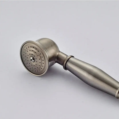 A sleek brushed stainless steel hand shower head with rounded nozzle in a vintage brass and bronze faucet set