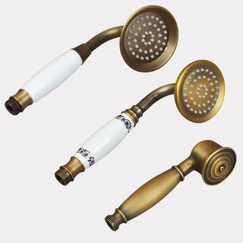 Three vintage-style brass and ceramic handheld shower heads with ceramic handles including one with black floral detailing