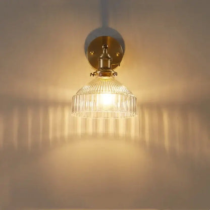 Vintage brass wall lamp with clear glass shade and pull chain switch providing warm light for bedroom use