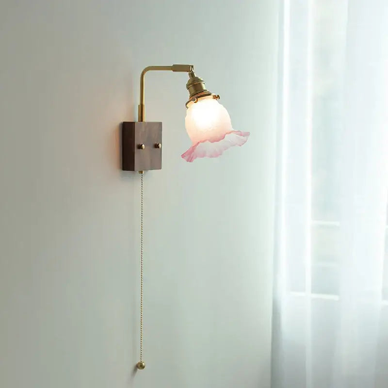 Vintage brass and glass pink led wall sconce with delicate ruffled glass and dark wood base for bedroom bedside use