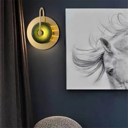 Gold-toned circular wall lamp with textured green glass diffuser and metal wall art light for living room decor