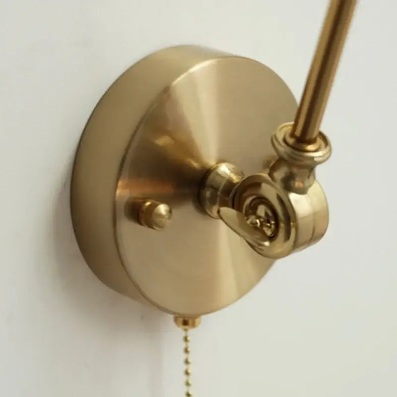Vintage brass and green glass wall light fixture with brass finish, circular base, and adjustable arm for bedroom use