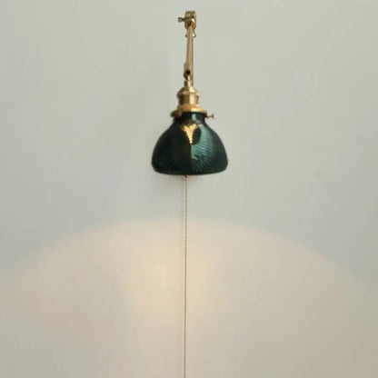 Vintage brass and green glass wall light fixture with pull-chain switch designed as a bedroom sconce light fixture