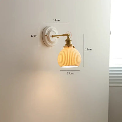 Cream-colored ribbed glass led wall light with brass-finished metal arm and mounting plate for bedroom sconce use