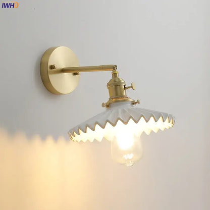 Brass-finished led wall lamp with scalloped white glass shade and exposed bulb for vintage bedroom lighting