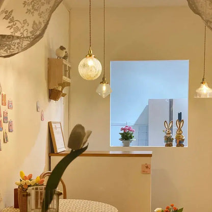 Warm-toned vintage brass and textured glass led pendant lamps hang from the ceiling in a dining room setting