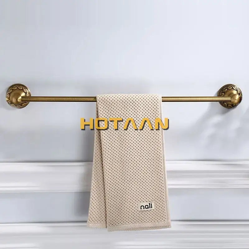 Beige textured towel with woven mesh pattern hanging on ornate vintage brass bathroom accessories set rack