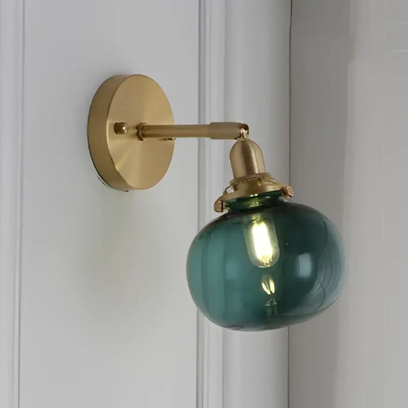 A sleek vintage brass wall lamp with rounded teal green clear glass globe led wall sconce for bedroom use