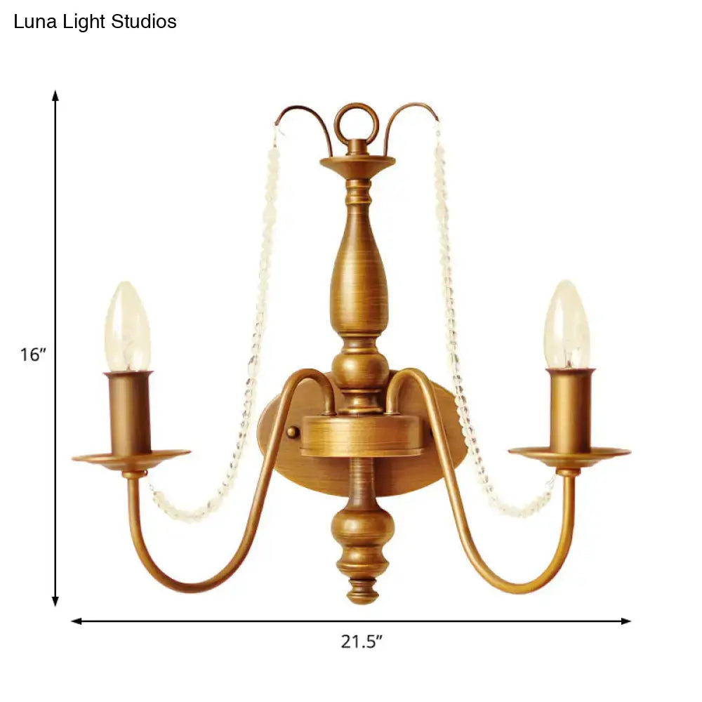 Antique brass two-light wall sconce with crystal bead chains and candle-style bulbs for vintage bedroom lighting