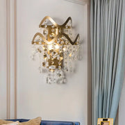 Vintage brass crystal wall sconce with gold-toned wavy frame direct wired bulb base and clear crystal leaf accents