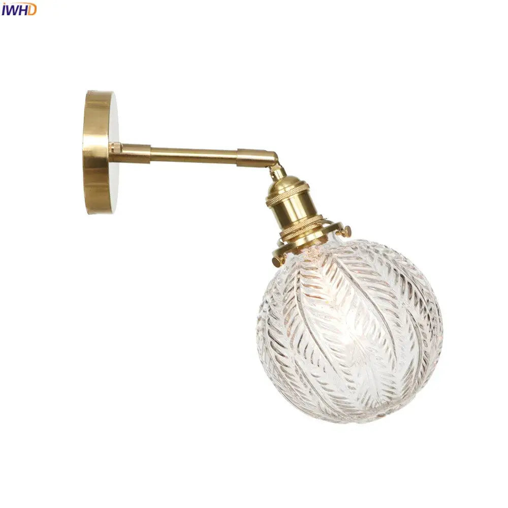 Brass-finished vintage led wall light featuring an intricately etched clear glass globe for bedroom use