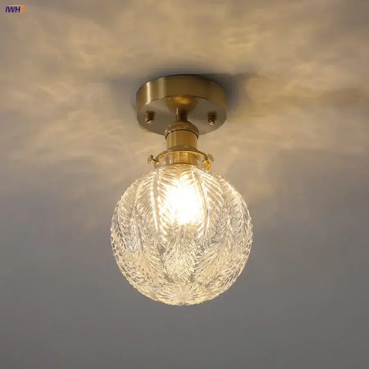 Vintage brass ceiling light with etched clear glass globe featuring intricate leaf patterns for living room use