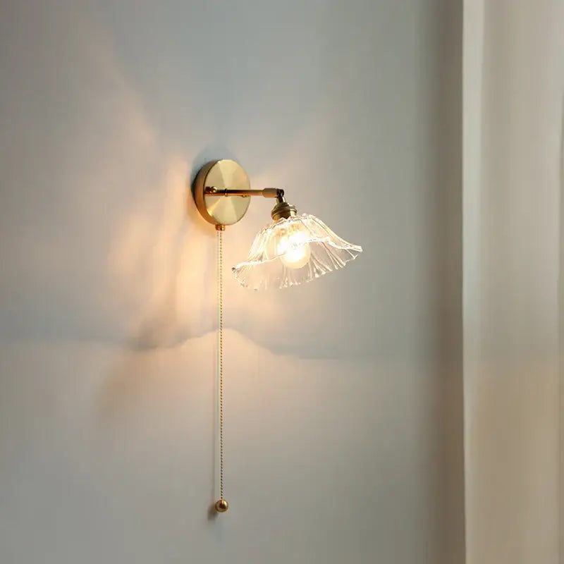 Vintage brass wall light with a clear fluted glass bedside sconce featuring an elegant pull-chain switch for bedroom decorbites