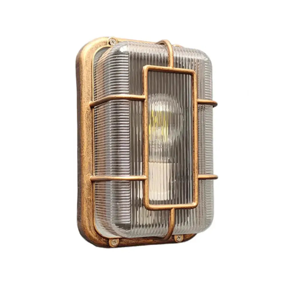 Vintage brass gas station canopy wall light with ribbed glass panel and protective metal cage for outdoor security