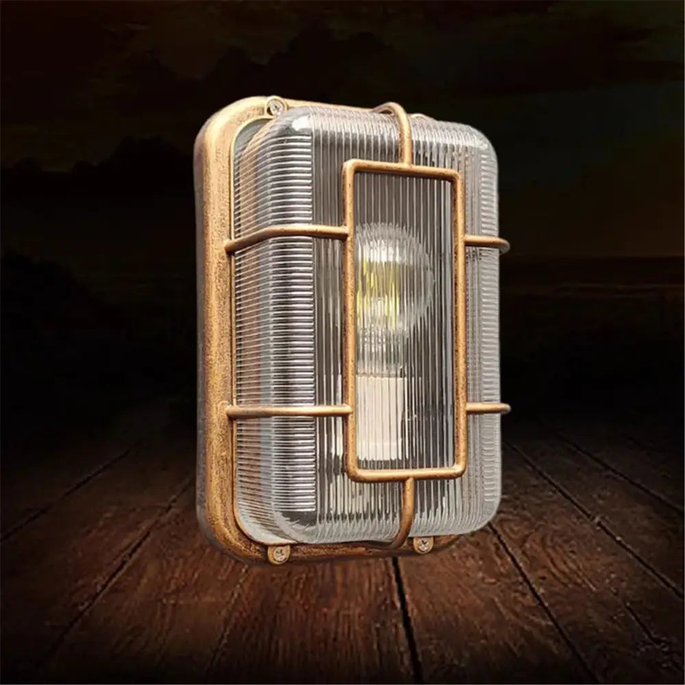 Industrial-style vintage brass gas station canopy wall light with clear ribbed glass and metal cage frame for outdoor use